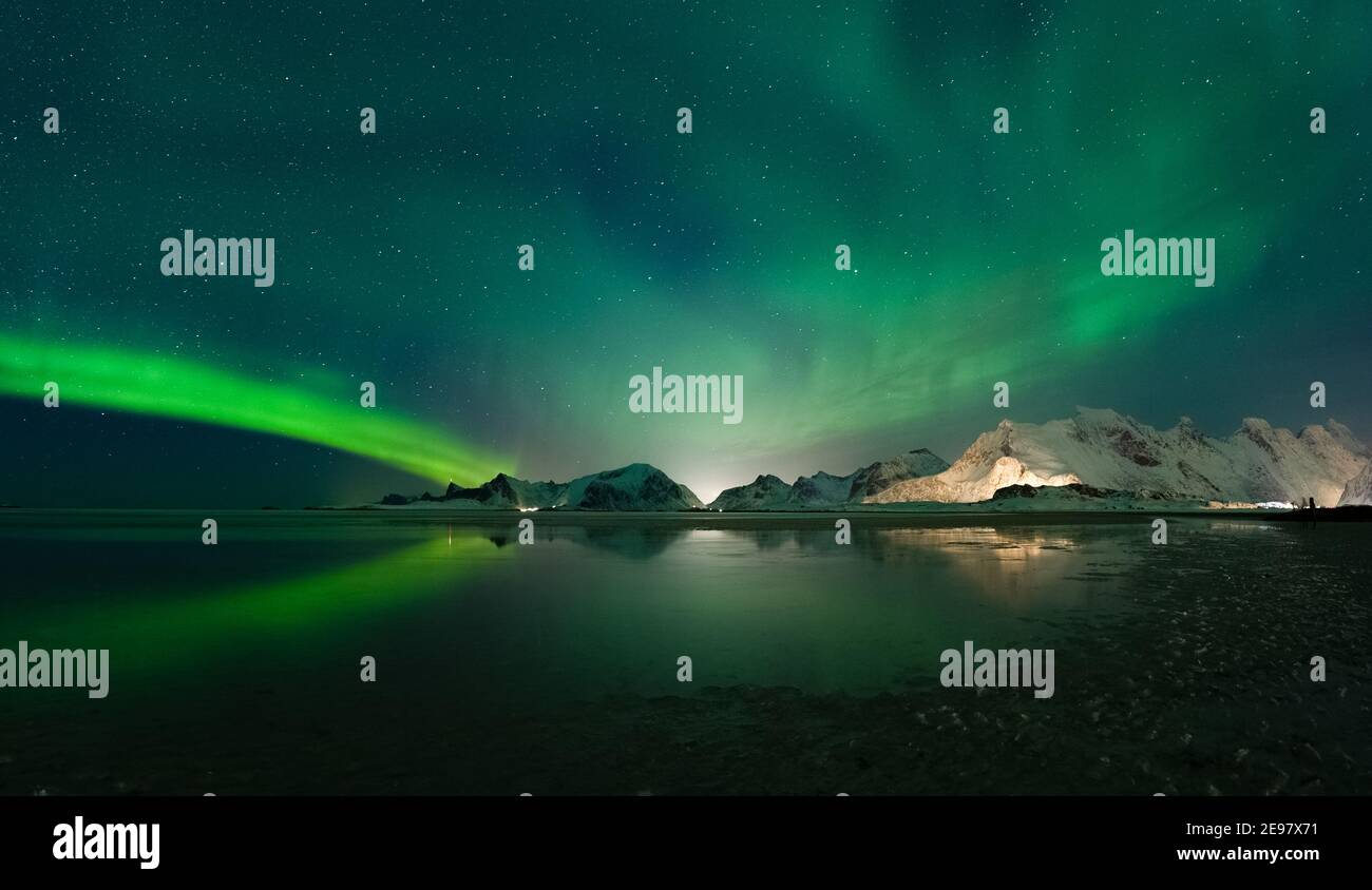 Aurora boreale sopra le montagne delle isole Lofoten. Riflessioni di Aurora Borealis sulla spiaggia sabbiosa di Sandbotnen. Belle condizioni invernali a nort Foto Stock