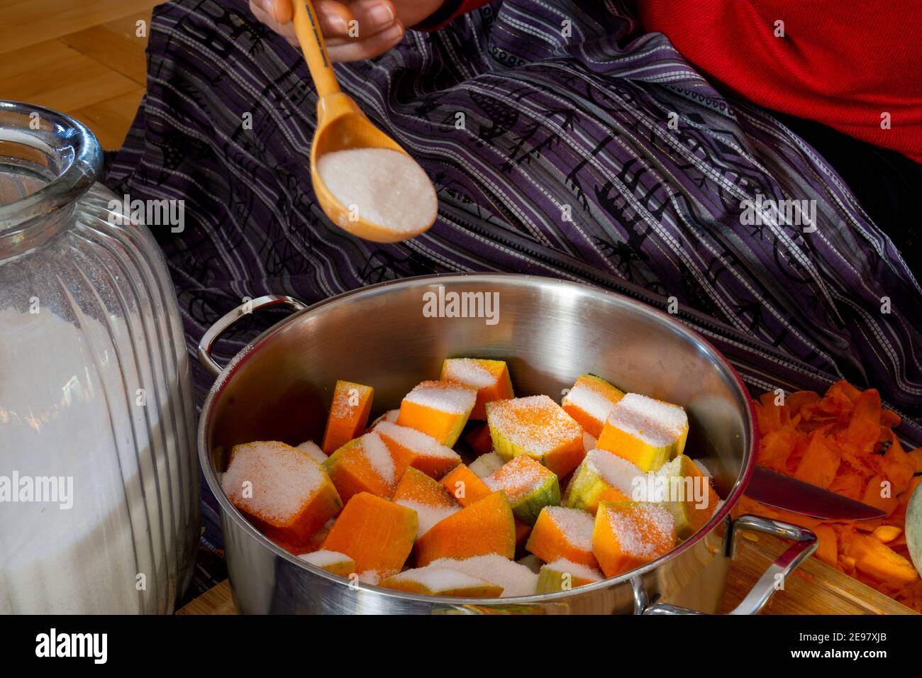 Fare la pasta dolce di zucca. Donna che taglia e affetta una zucca sul tagliere mentre si siede sul pavimento in cucina a casa. Foto Stock