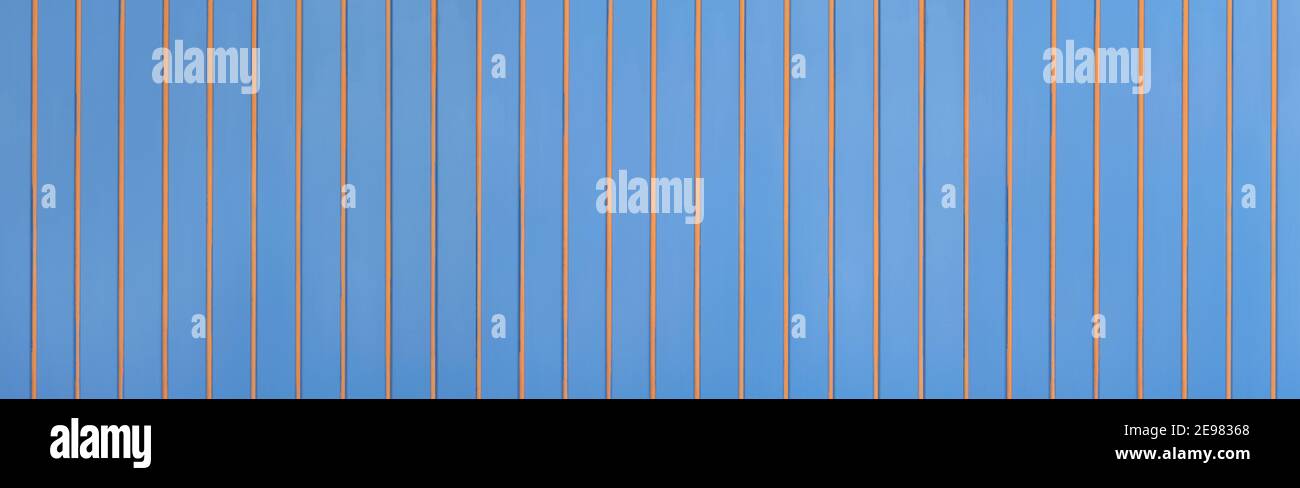 Parete di legno blu con strisce di legno arancione applicate, verticali Foto Stock