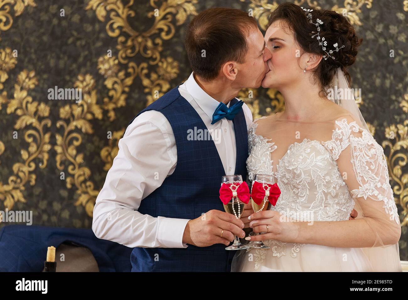 la sposa e lo sposo baciano e ballano in un ristorante, la felicità degli sposi alla cerimonia nuziale, un bacio romantico Foto Stock