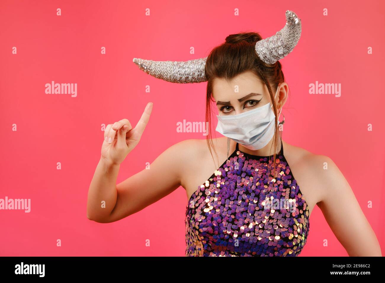 Segno zodiacale Toro. Astrologia e concetto oroscopo, bella donna con maschera medica, corna e trucco creativo su sfondo rosso Foto Stock