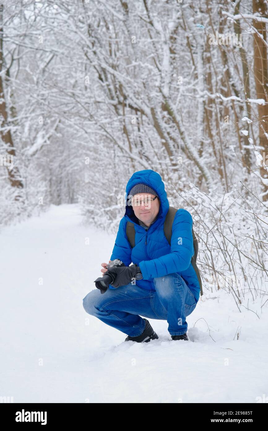 fotografa con una fotocamera che sbatte nella foresta invernale guardando la macchina fotografica Foto Stock