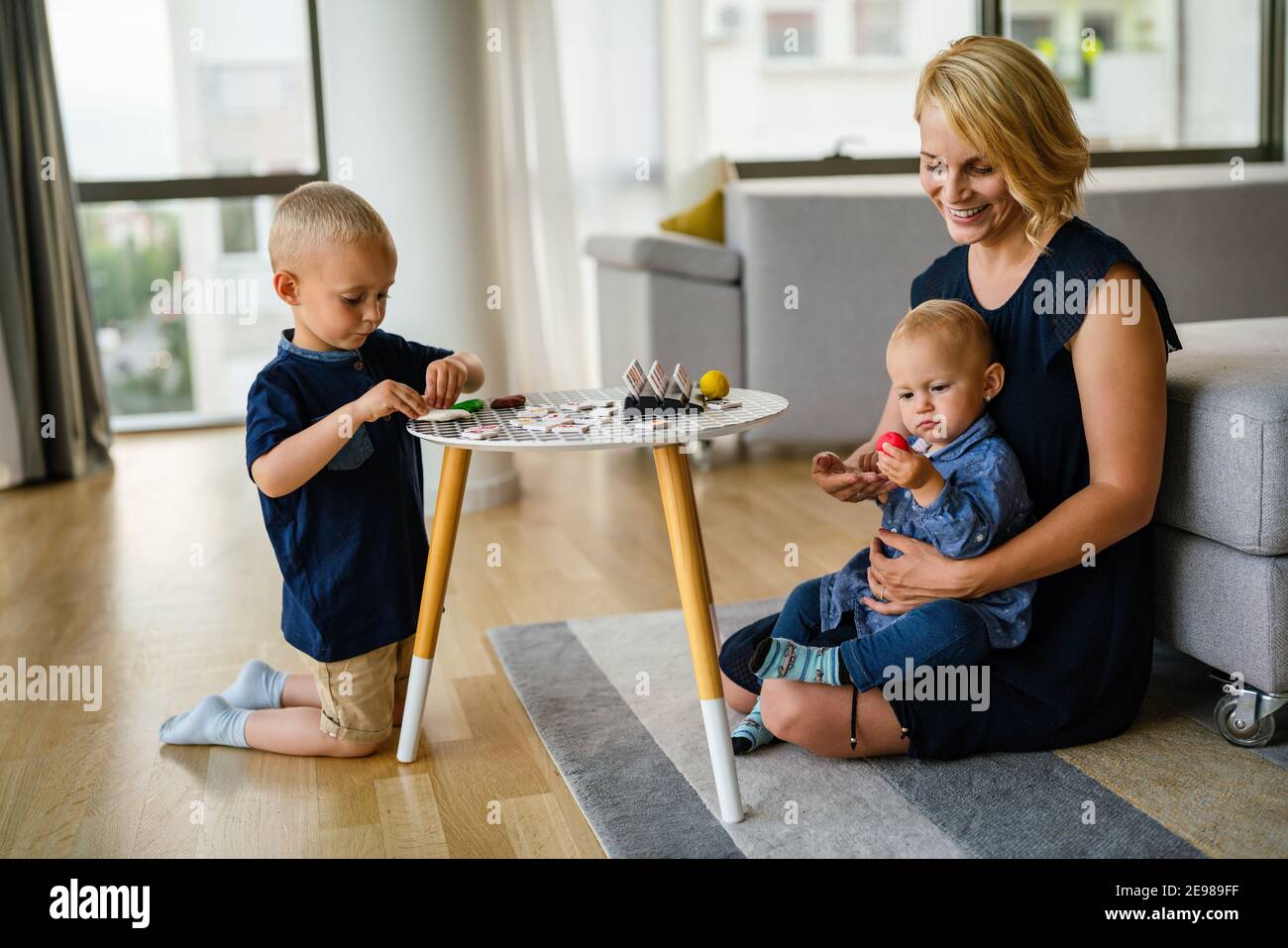 Madre o insegnante di vivaio insegna ai suoi figli a lavorare con giochi di argilla colorati Foto Stock