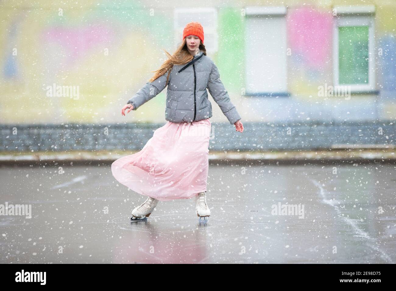 Ragazza adolescente pattina su ghiaccio nella città.giovane ragazza in un  vestito lungo e una giacca calda sul ghiaccio Foto stock - Alamy