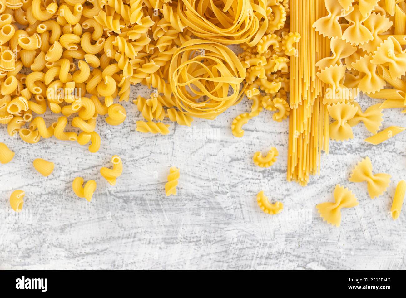 Vari tipi di pasta Farfalle, Pasta A riso, Orecchiette Pugliesi, Gnocco Sardo e Farfalle su fondo di pietra bianca con posa piatta. Cucina italiana c Foto Stock