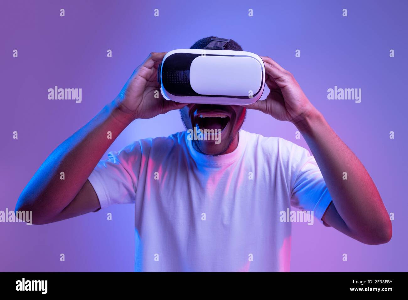 Concetto di gioco virtuale. Simpatico Black Guy indossa occhiali VR, Neon Light Foto Stock