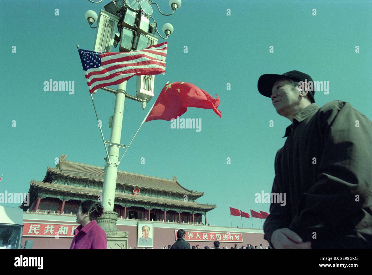 Un uomo cinese cammina oltre le bandiere cinesi e americane che volano sopra l'area intorno a Piazza Tiananmen quando George W. Bush visita la Cina. 2002 Foto Stock