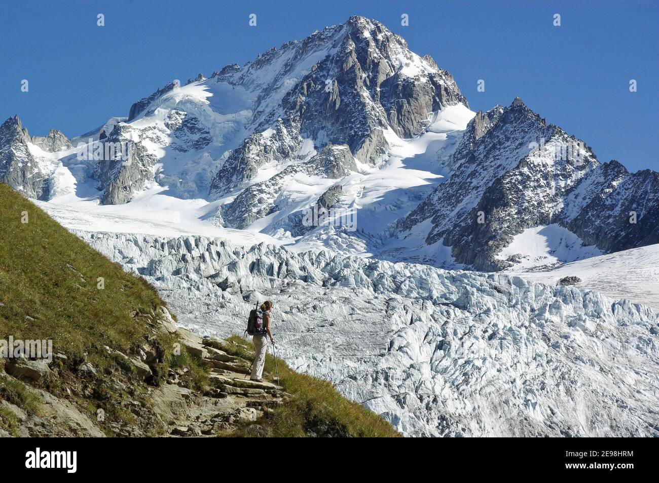Una signora escursionista sul sentiero da lac Charamillon al Rifugio Albert Premier nelle Alpi francesi, con l'Aiguille de Chardonnet e il ghiacciaio Du To Foto Stock