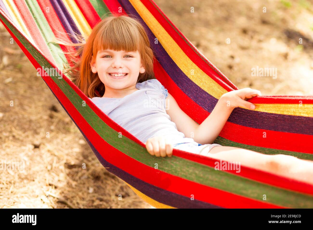 Vacanze estive. Bella bambina riposa in amaca colorata all'aperto nella foresta estiva Foto Stock