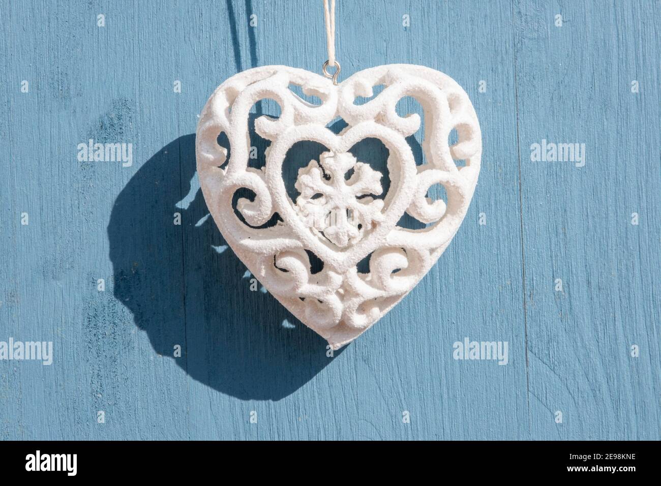 Concetto di amore e saluti: Vista dall'alto su un singolo cuore scolpito, bianco appeso su uno sfondo blu in legno con spazio per la copia. Celebrazione Foto Stock