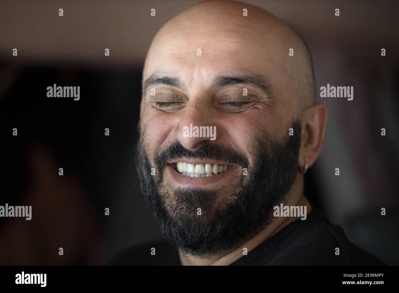 Primo piano ritratto di calvo con bei denti bianchi sorridendo a grandi linee con gli occhi chiusi Foto Stock