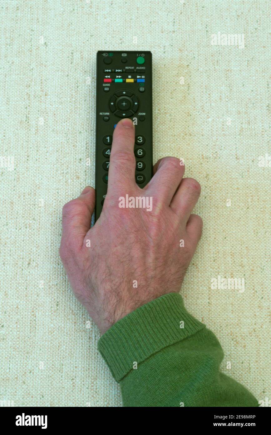Mano dell'uomo che tiene il telecomando del televisore Foto Stock