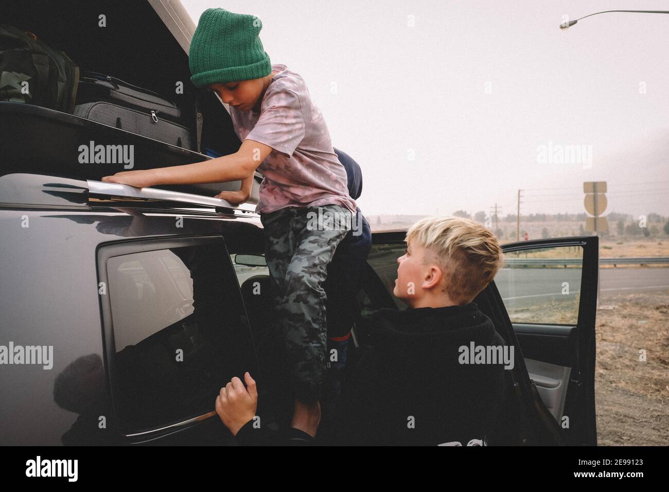 I fratelli che si sono dati il check-in su un portapacchi durante un viaggio su strada. Foto Stock