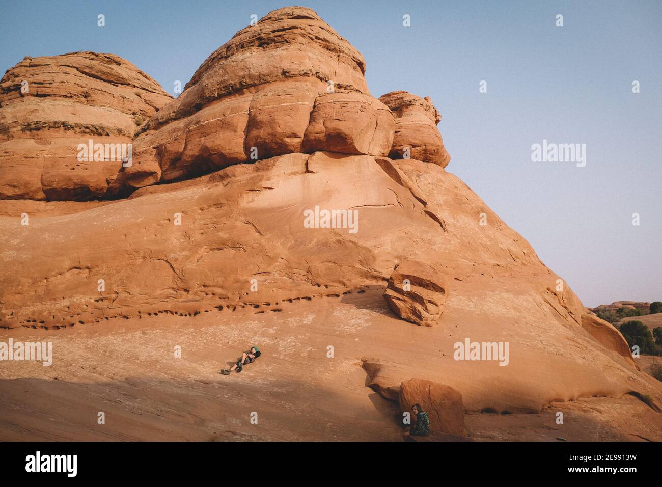 Due ragazzi si rilassano su una roccia del deserto da lontano. Foto Stock