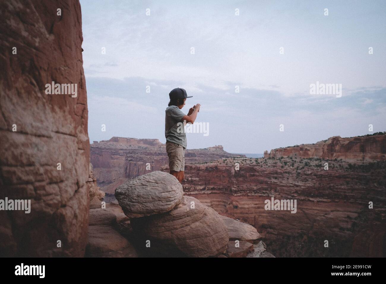 Ragazzo scattando una foto da una scogliera bordo in Canyonlands Parco nazionale Foto Stock