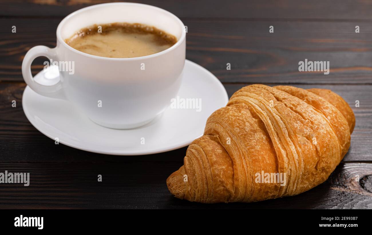 tazza di caffè e croissant su tavolo di legno. Vista dall'alto. Foto Stock