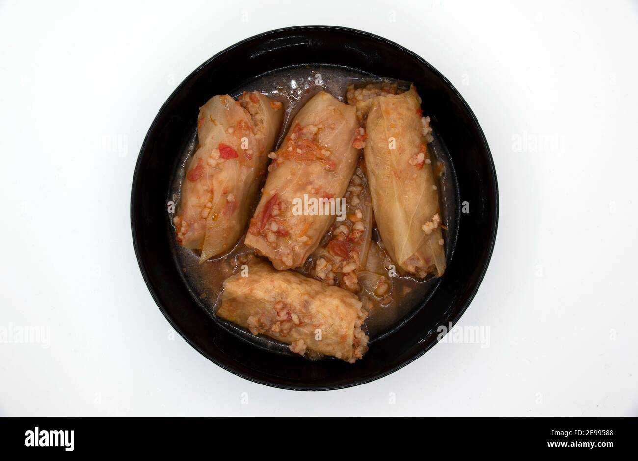 Un piatto di involtini di cavolo in un piatto nero, che è carne macinata con riso bollito, avvolto in foglie di cavolo. Foto Stock