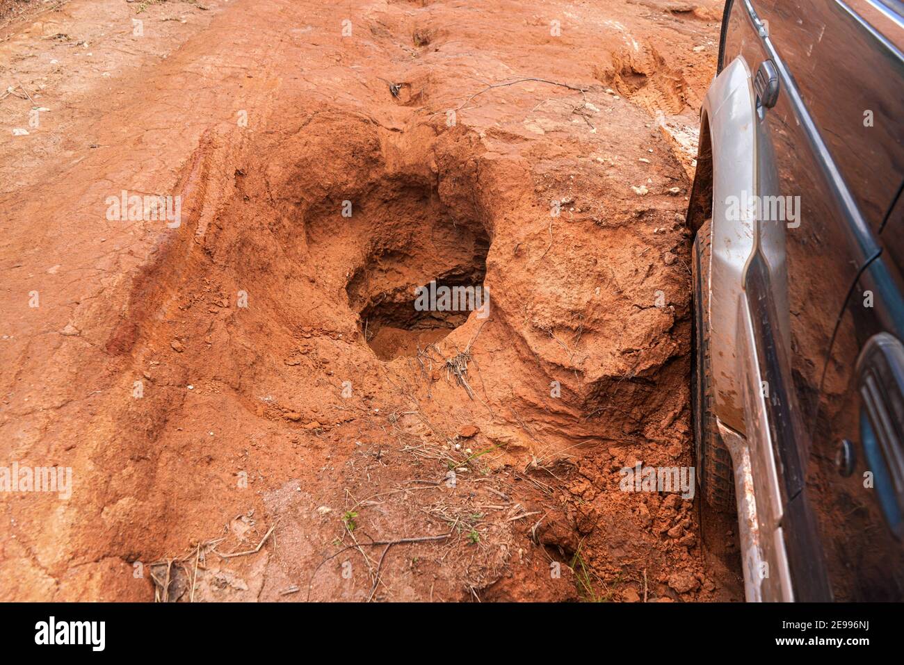 Guida di un veicolo 4wd su una strada di campagna rossa polverosa con grandi buche, dettaglio degli pneumatici che si staziona su terreni accidentati. Le strade sono in cattive condizioni in Madagascar Foto Stock