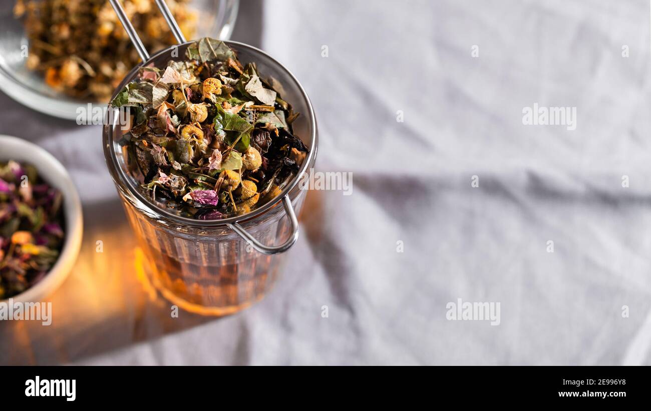 Tè alle erbe con camomilla, rosa e menta su sfondo grigio con spazio copia. Concetto di rimedio domestico Foto Stock