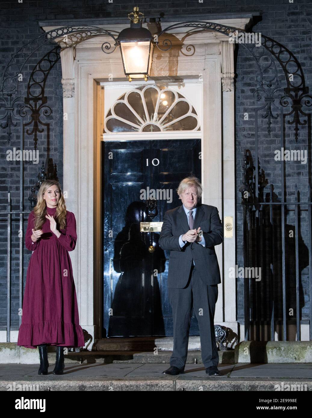 Il primo ministro Boris Johnson e il suo partner Carrie Symonds si trovano fuori 10 Downing Street, Londra, per unirsi a un clap a livello nazionale in onore del capitano Sir Tom Moore, il 100-year-old fundraiser di beneficenza che è morto il martedì dopo test positivi per Covid-19. Data immagine: Mercoledì 3 febbraio 2021. Foto Stock