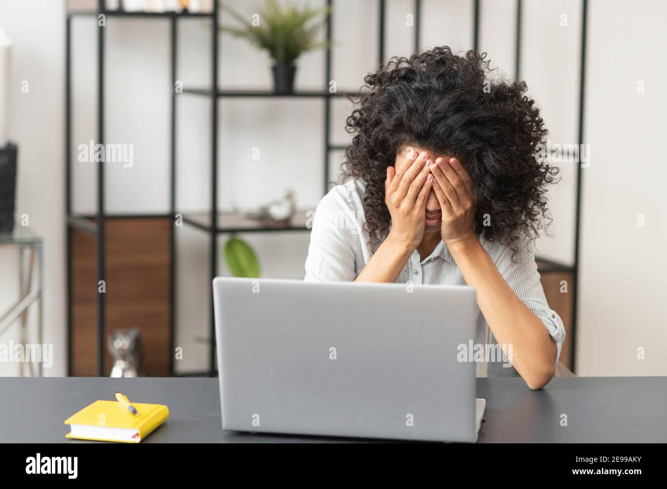 La lotta di scadenza, la giovane donna africana americana lavoratrice di ufficio con afro acconciatura sensazione stanco, esausto, e overworked, seduto con Foto Stock