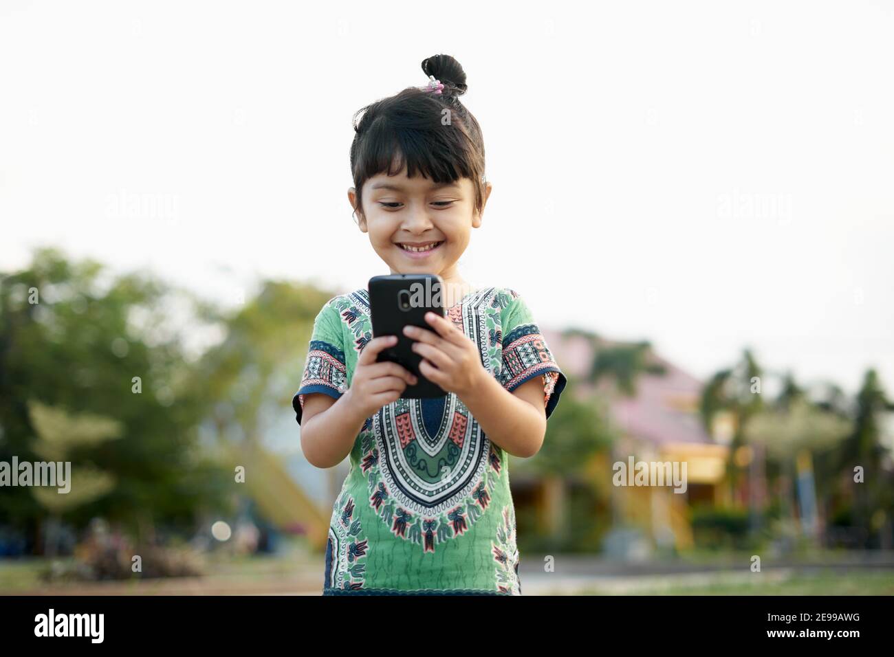 Ritratto di bambina carina con smartphone al pubblico parcheggio Foto Stock