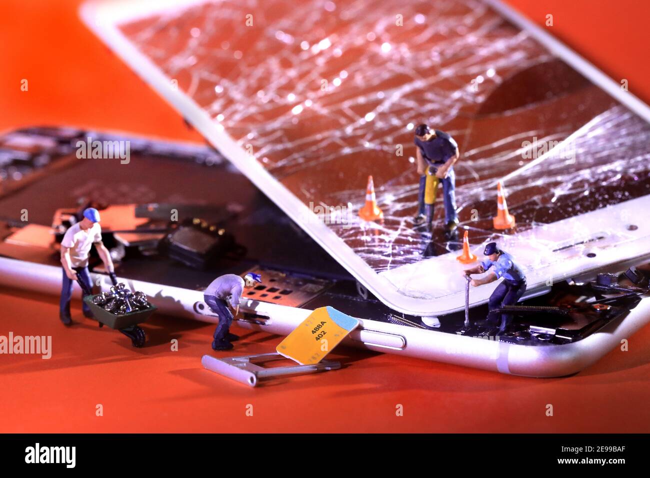 Persone in miniatura che riparano e riparano un iPhone rotto Foto Stock