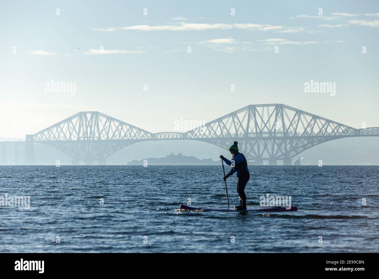 Un paddle boarder godendo del sole invernale sul Firth of Forth vicino al Forth Bridge, al Saint Davids Bay Fife Foto Stock