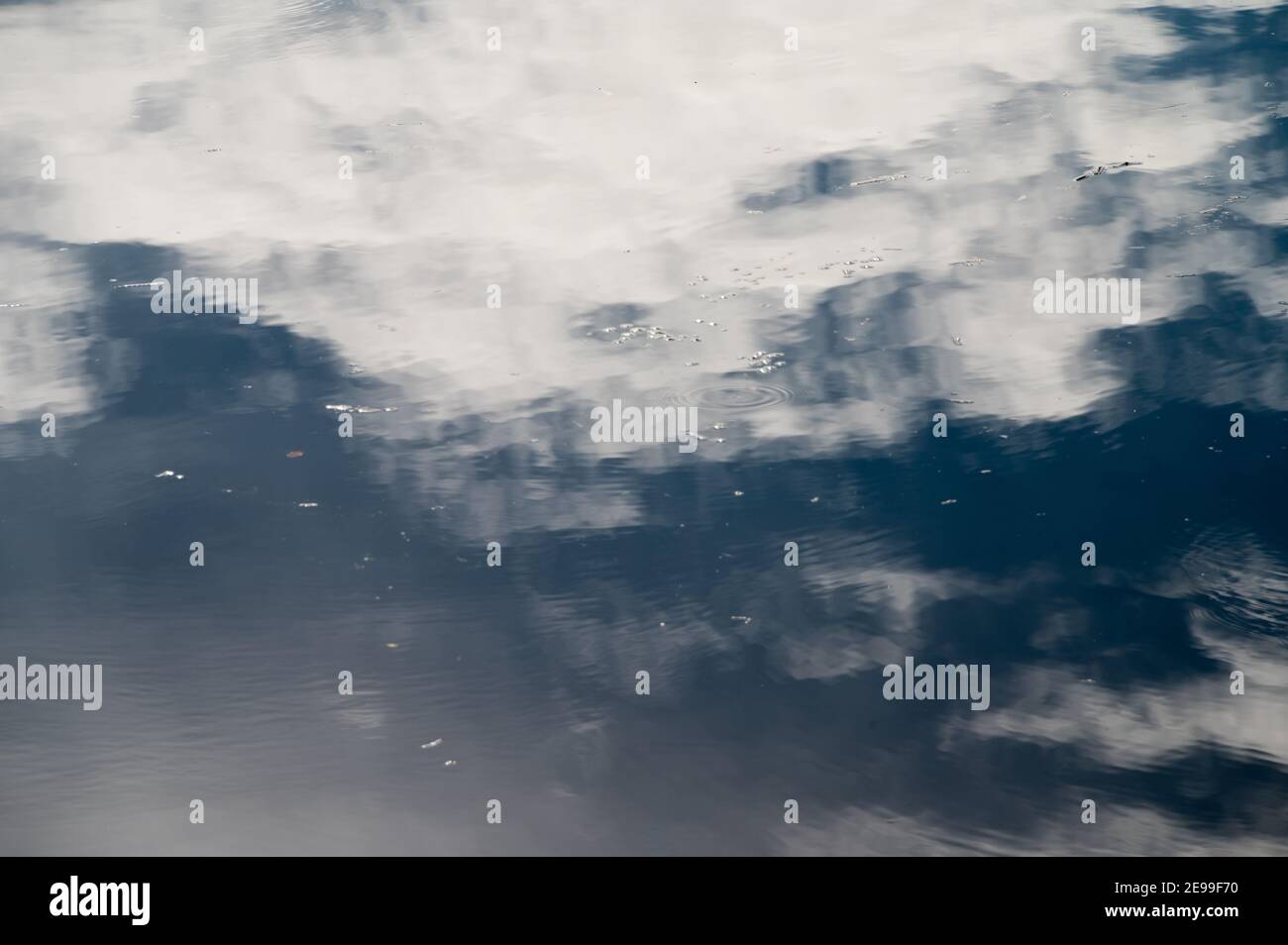 Il cielo nuvoloso si riflette nel lago con piccole bolle d'acqua superficie Foto Stock