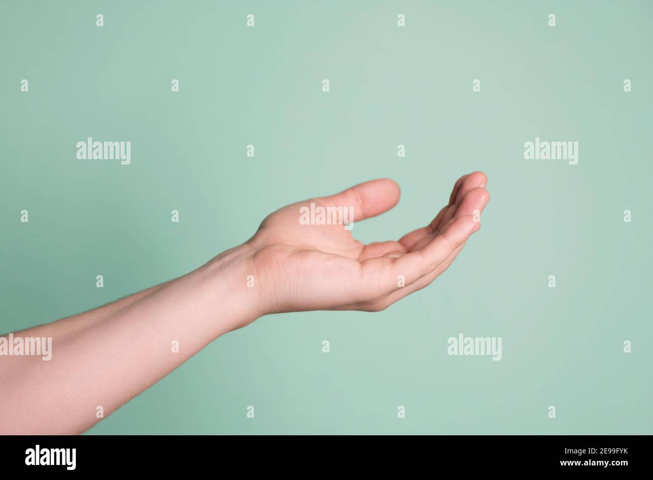 Primo piano della mano maschile con palmo aperto isolato su sfondo blu. Foto Stock