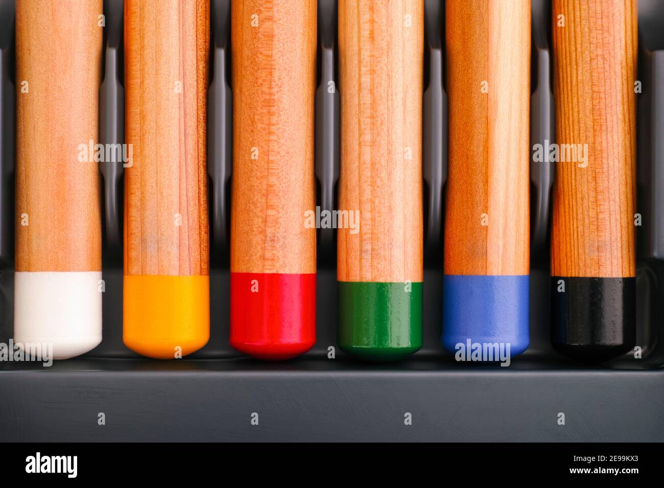Il fondo di sei matite colorate in una fila in vassoio grigio Foto Stock