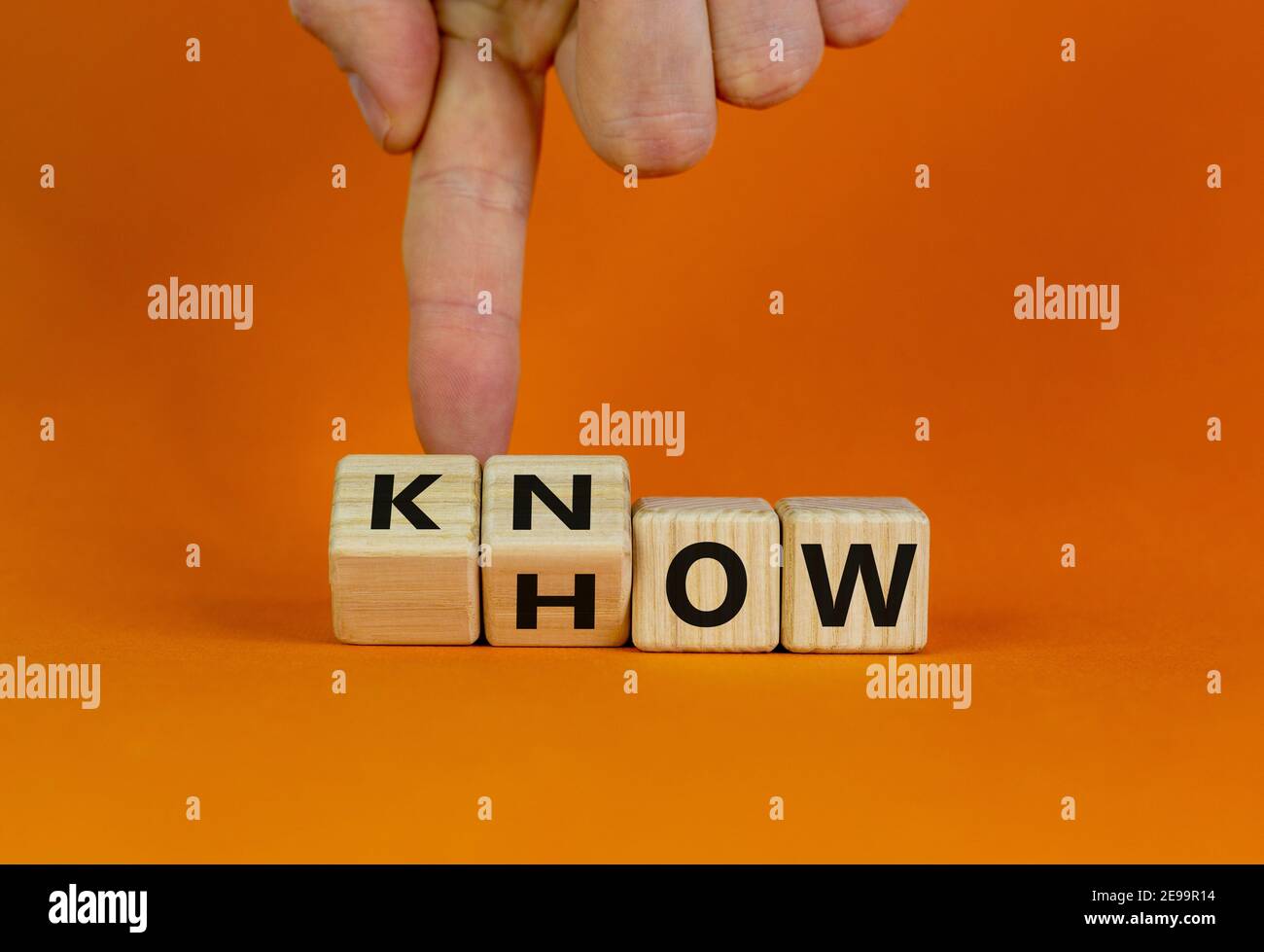 Conoscere il simbolo. L'uomo d'affari gira i cubi e cambia la parola 'come' a 'sapere'. Bellissimo sfondo arancione. Spazio di copia. Business e know how concetto. Foto Stock