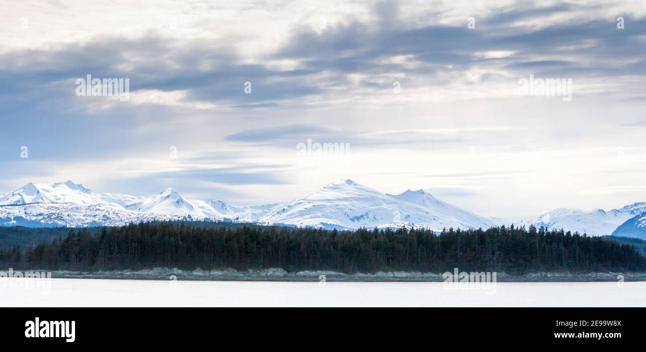 Vista panoramica sulle montagne innevate e sugli alberi sempreverdi lungo Costa dell'Alaska meridionale Foto Stock