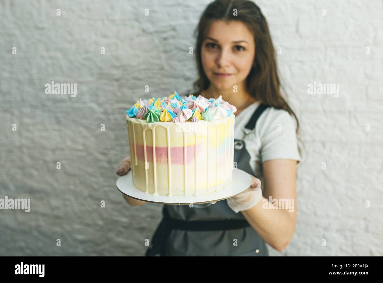 una ragazza pasticciera tiene in mano una torta preparata. Foto Stock