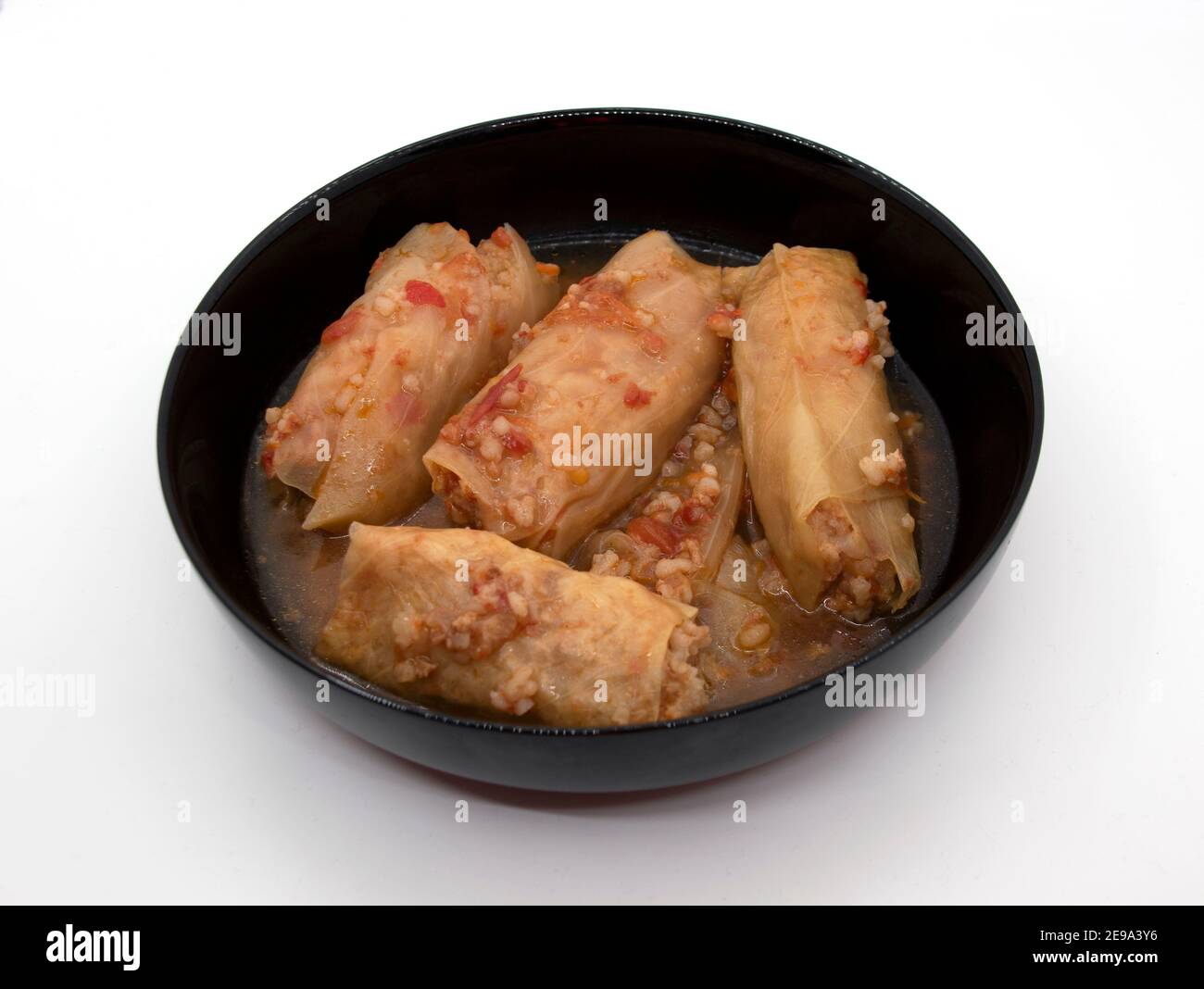 Un piatto di involtini di cavolo in un piatto nero, che è carne macinata con riso bollito, avvolto in foglie di cavolo. Foto Stock