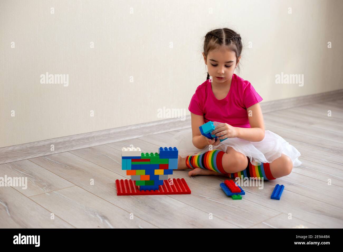 Gioco di ragazza con costruttore di plastica multicolore sul pavimento Foto Stock