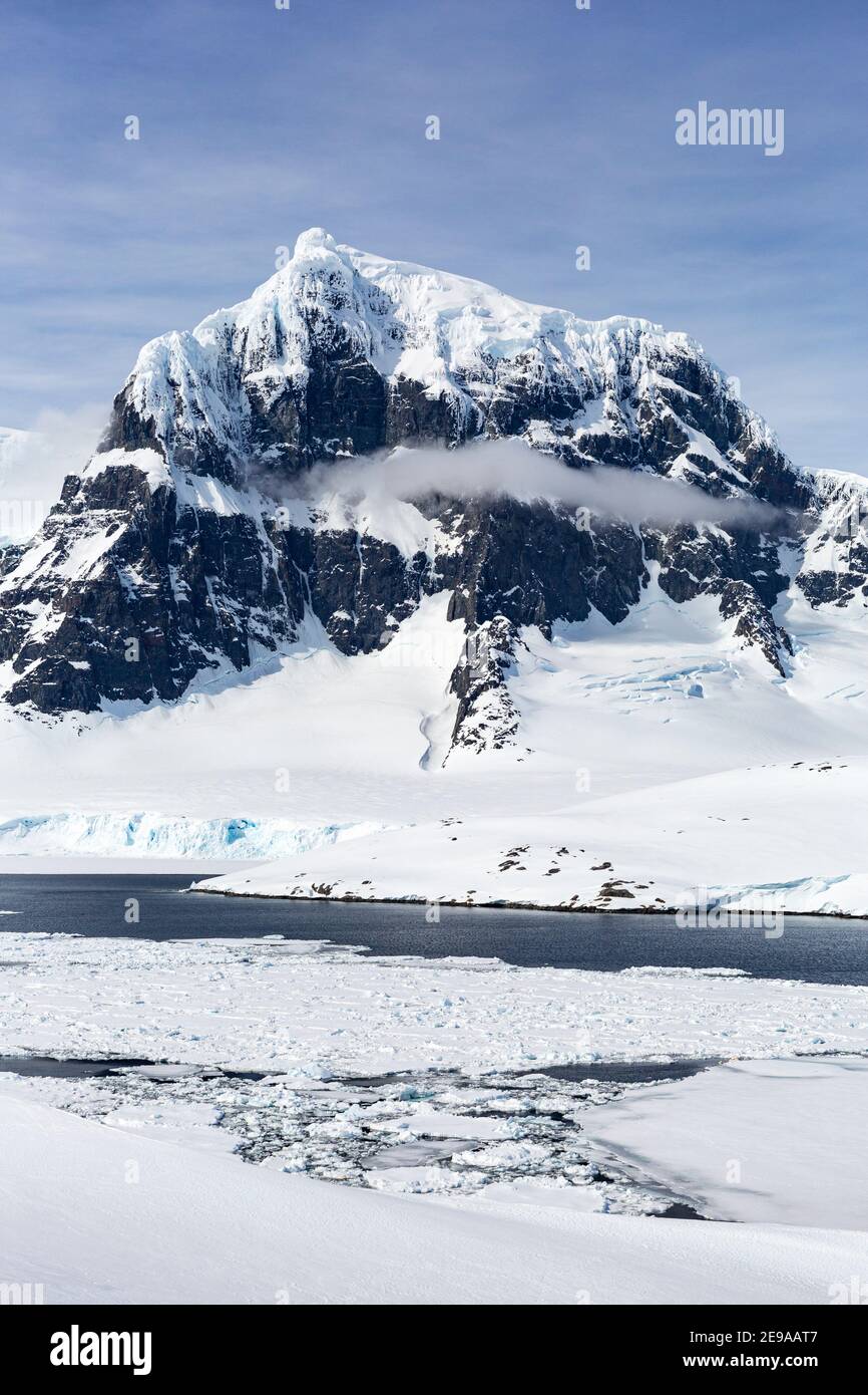 Montagne innevate e ghiaccio marino denso nel canale di Neumayer, Arcipelago di Palmer, Antartide. Foto Stock