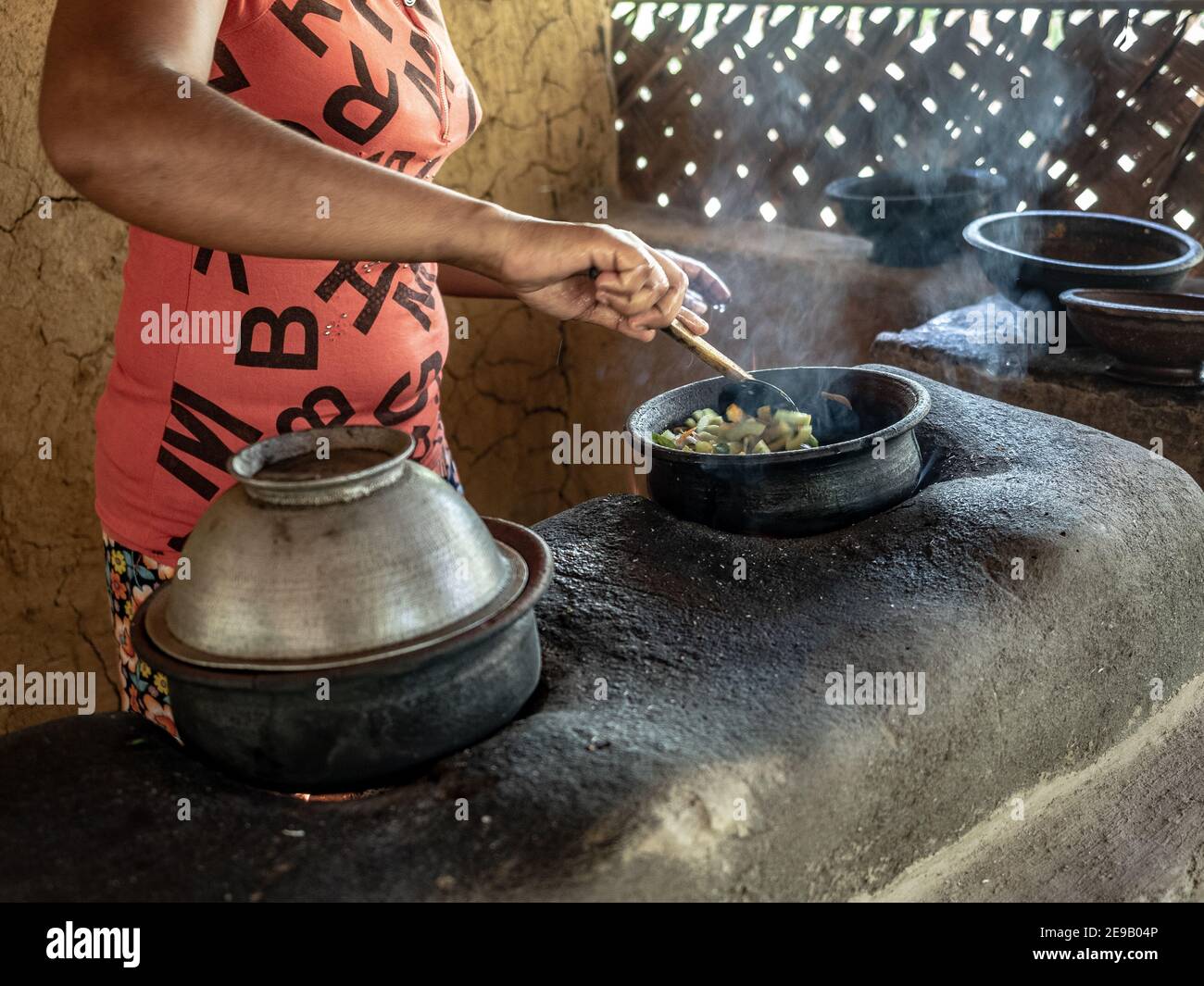 HIRIWADUNNA, SRI LANKA - 10 marzo 2019: Giovane donna del sud asiatico che cucina riso e curry nella cucina rurale tradizionale all'aperto. Foto Stock