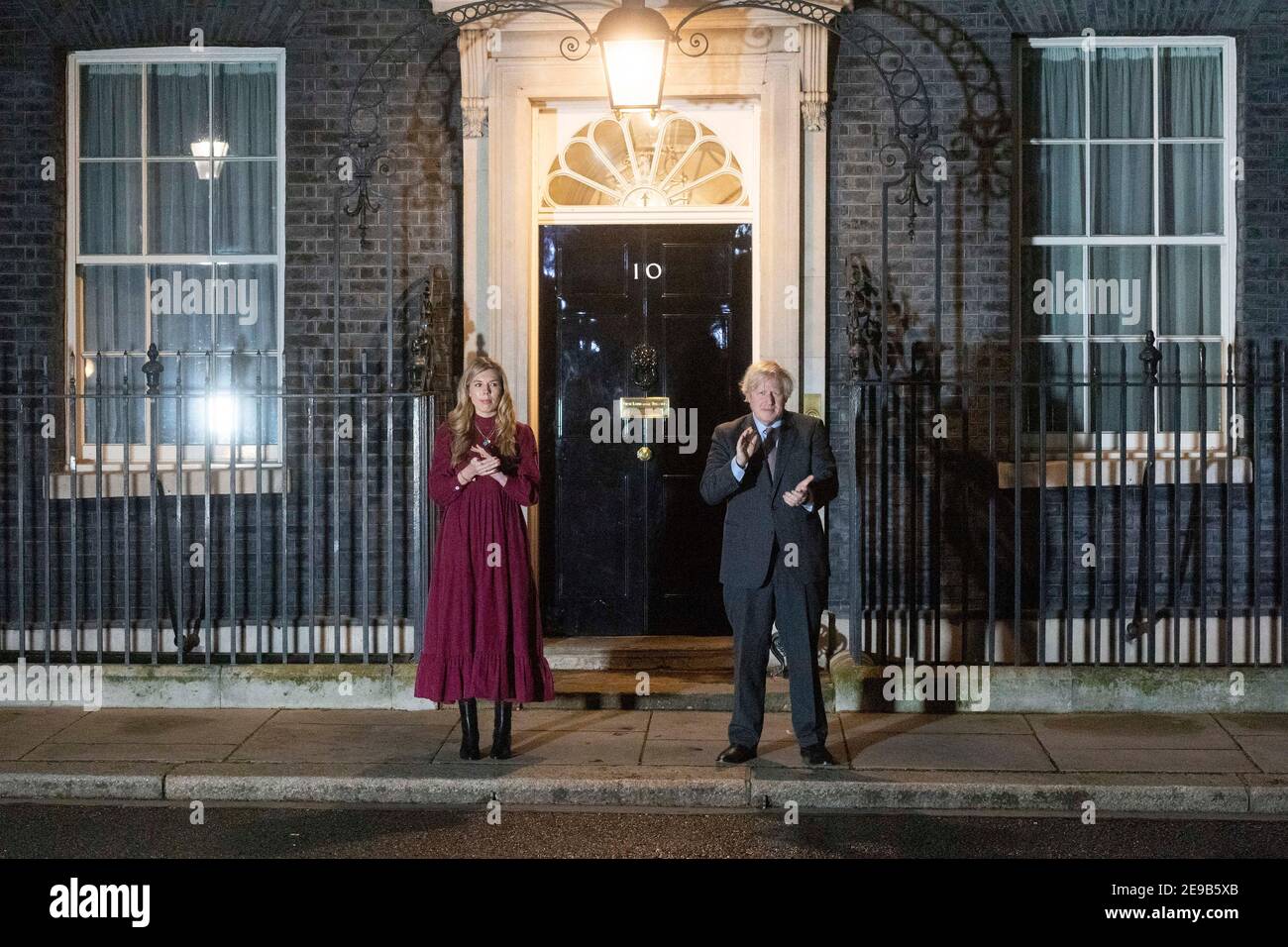 03 febbraio 2021. Londra, Regno Unito. Il primo ministro britannico Boris Johnson e il suo partner Carrie Symonds si sono aggrappati alle porte di 10 Downing Street per onorare il capitano Tom Moore. Johnson ha incoraggiato la popolazione della Gran Bretagna a partecipare ad un clap pubblico più tardi questa sera, in riconoscimento del famoso servizio sanitario di beneficenza Raiser Captain Tom che è morto Martedì. Foto di Ray Tang. Foto Stock