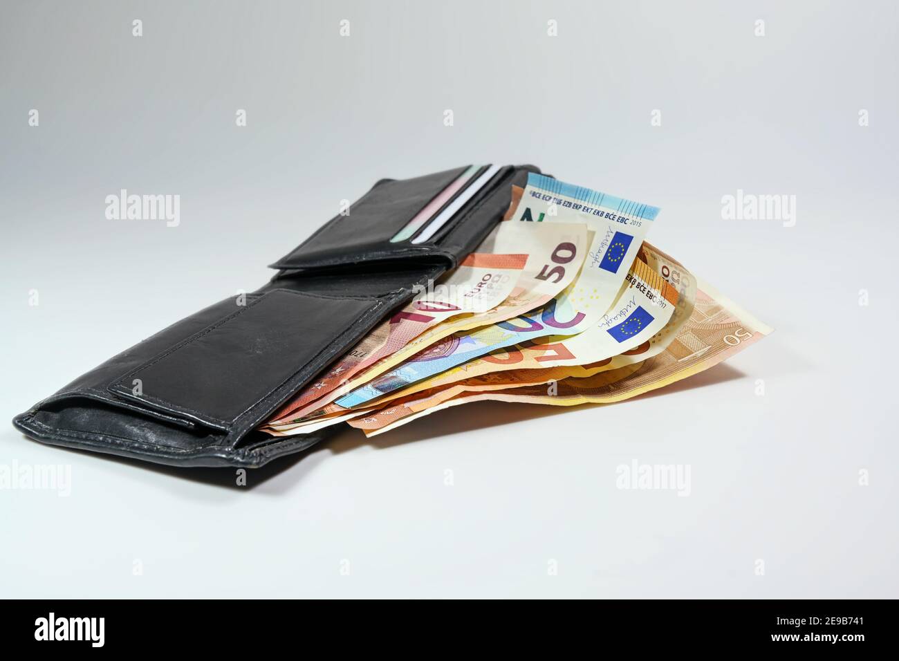 Portafoglio in pelle nera con numerose banconote in euro su sfondo grigio chiaro, concetto di denaro per il successo finanziario, spazio di copia, fuoco selezionato, narro Foto Stock