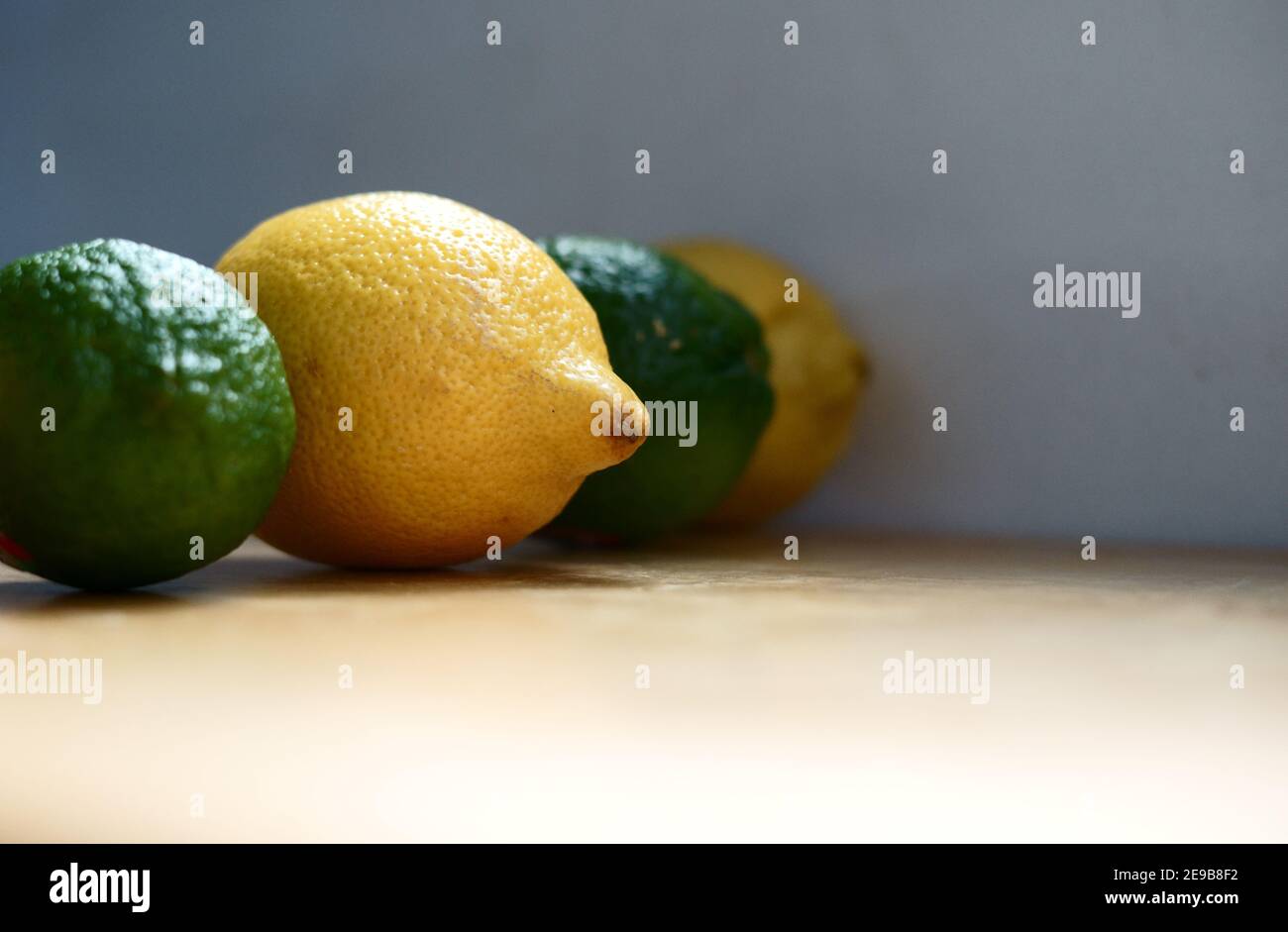 Ritratto di ingredienti freschi e biologici: Una fila di limone e lime con una particolare attenzione al limone fresco e biologico. Foto Stock