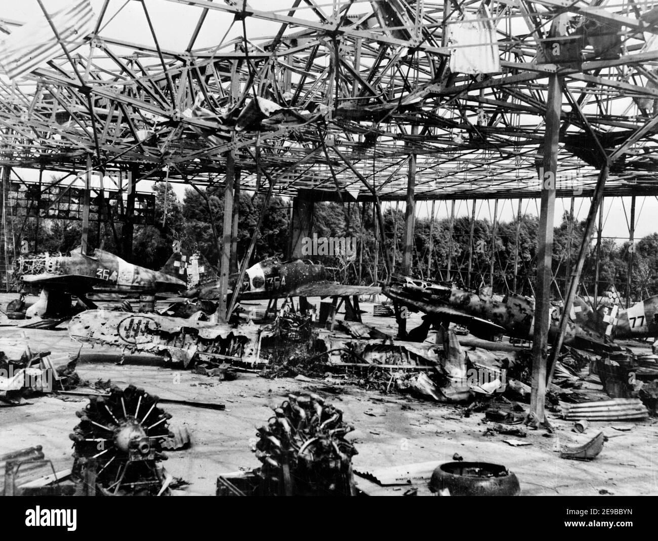 I combattenti italiani sono stati distrutti in un hangar distrutto all'aeroporto di Castel Benito, Tripolis, Libia, all'inizio del 1943. Sono visibili tre personaggi Macchi MC.200 Saetta e un unico MC.202 Folgore (2° piano da destra). Foto Stock