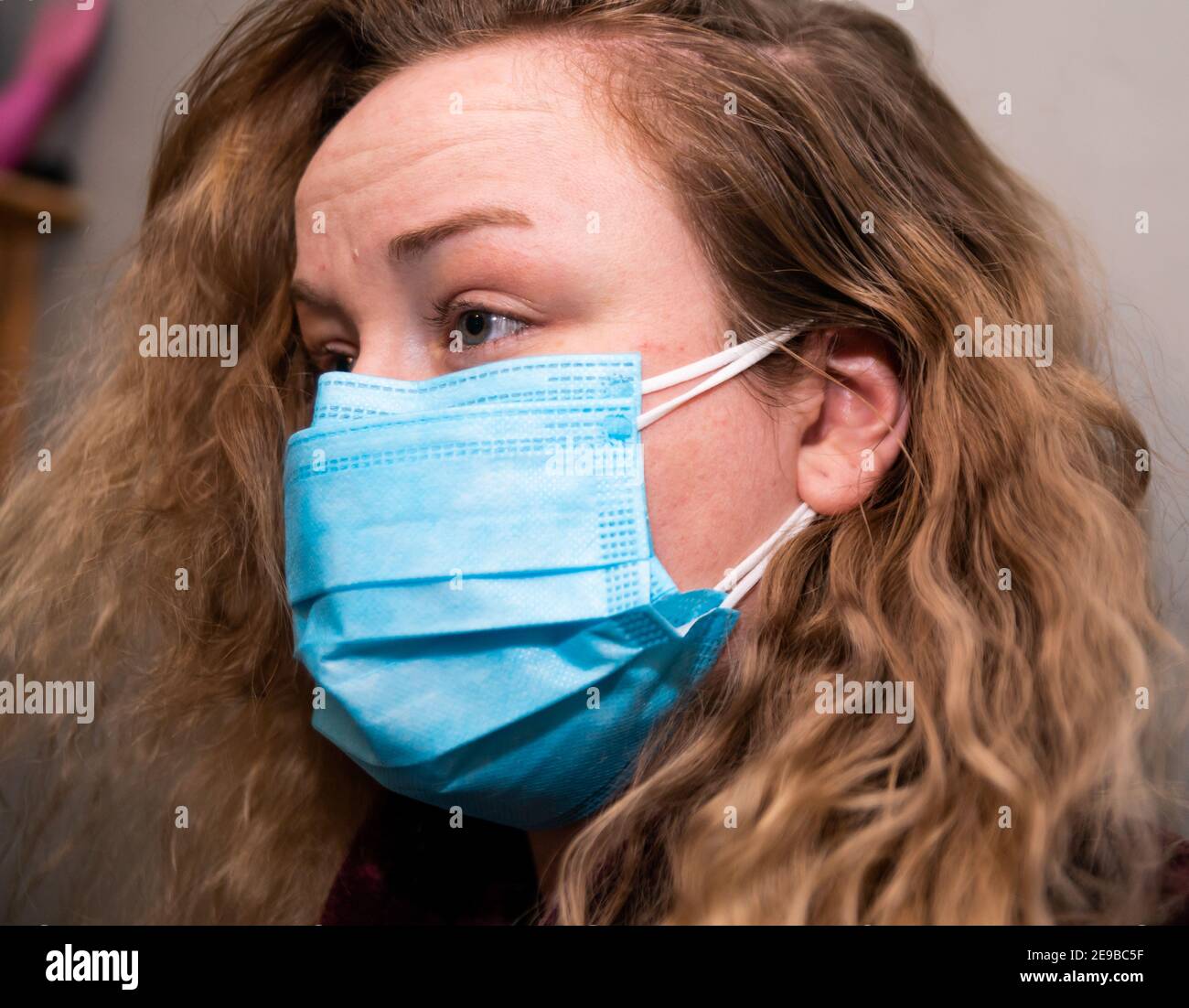 Donna bianca che indossa maschere doppie per la prevenzione covid, colpo laterale, capelli biondi Foto Stock