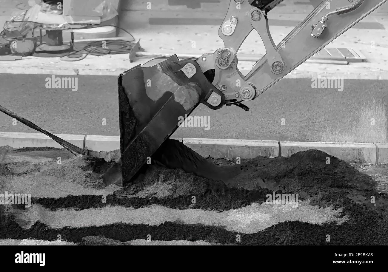 Artiglio di un digger giallo, si muove intorno alla sabbia, aiutato manualmente da un rastrello d'acciaio. Foto Stock