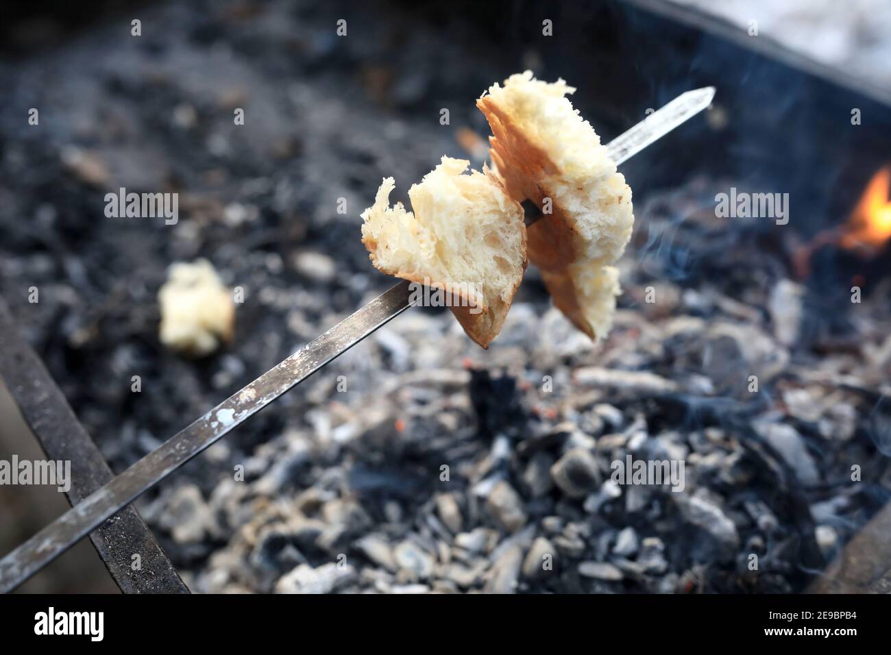 Tostatura del pane sulle calette in un picnic Foto Stock
