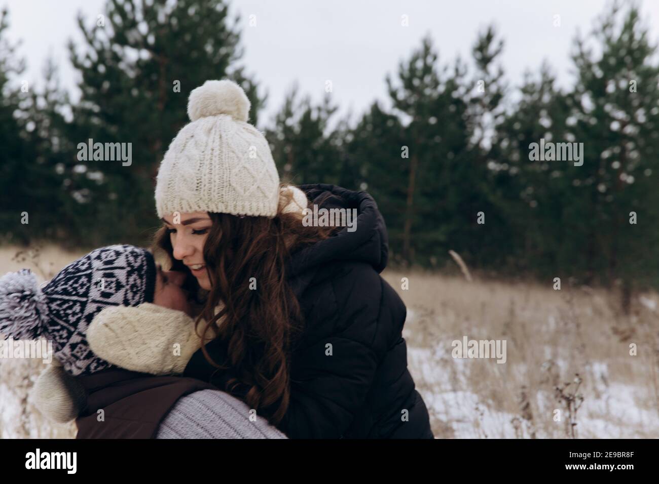 Un uomo e una donna si baciano sullo sfondo di pini verdi e neve bianca Foto Stock