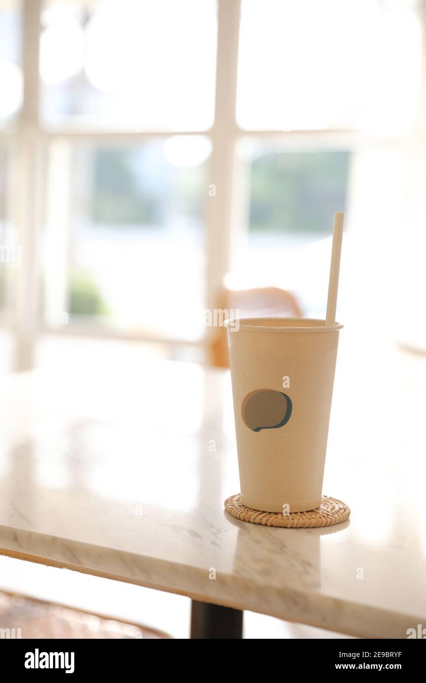 Caffè ghiacciato con vetro di carta sullo sfondo della caffetteria Foto Stock