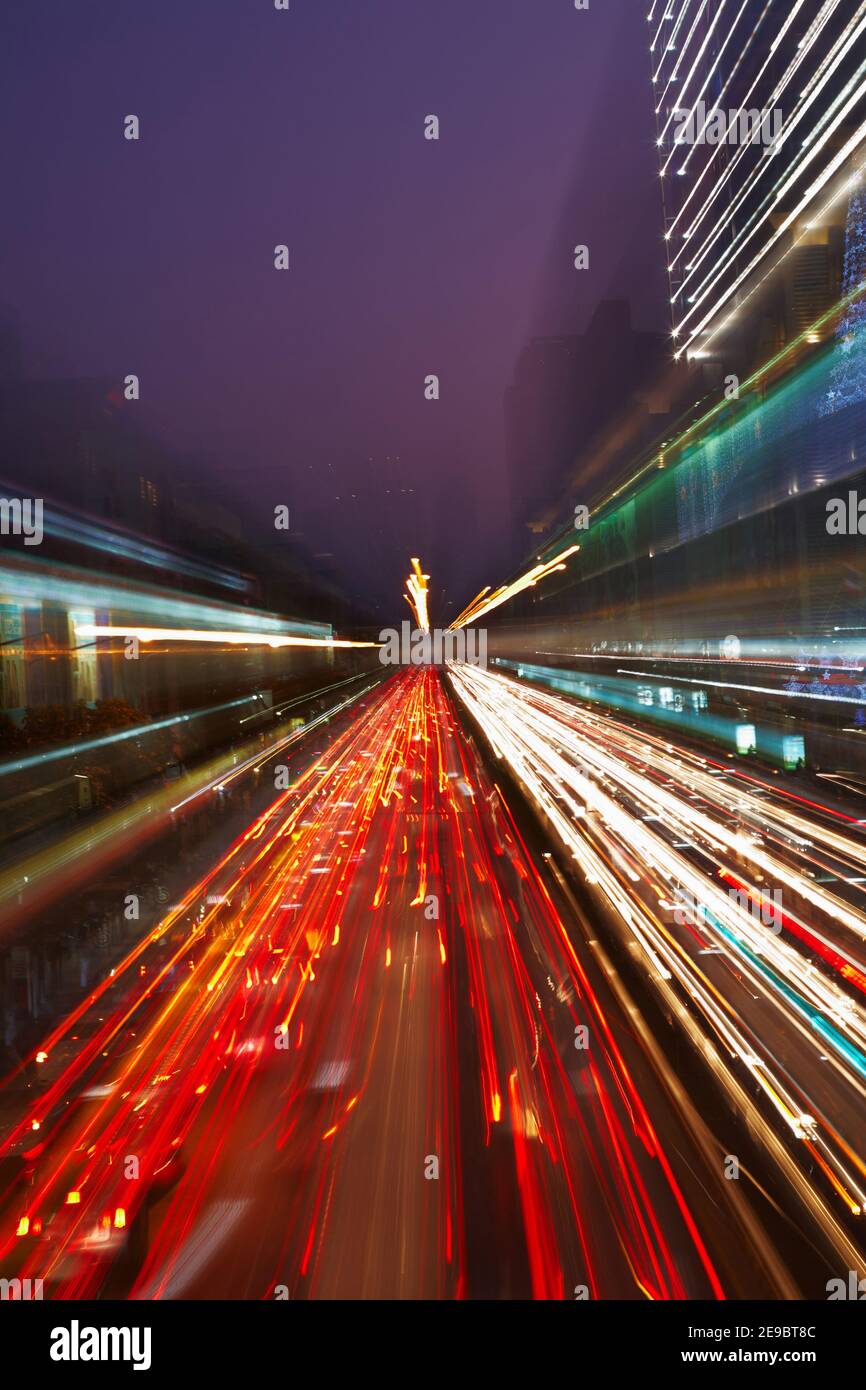 Traffico notturno in città, le luci dell'auto in movimento si sfuocano con effetto zoom Foto Stock