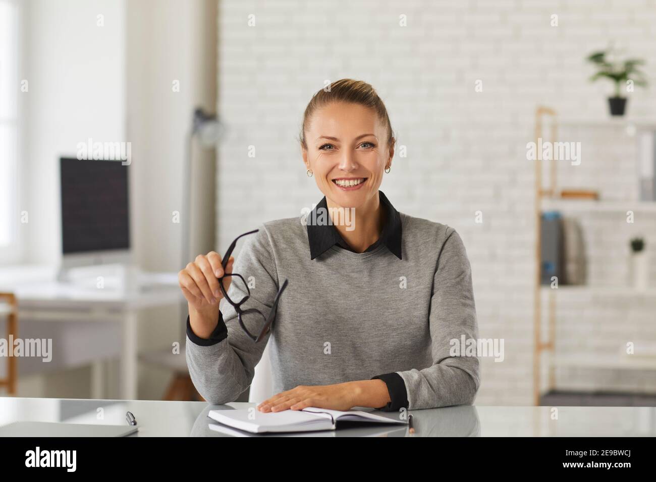 Donna manager con gli occhiali in mano e tiene un incontro online con i suoi clienti. Foto Stock