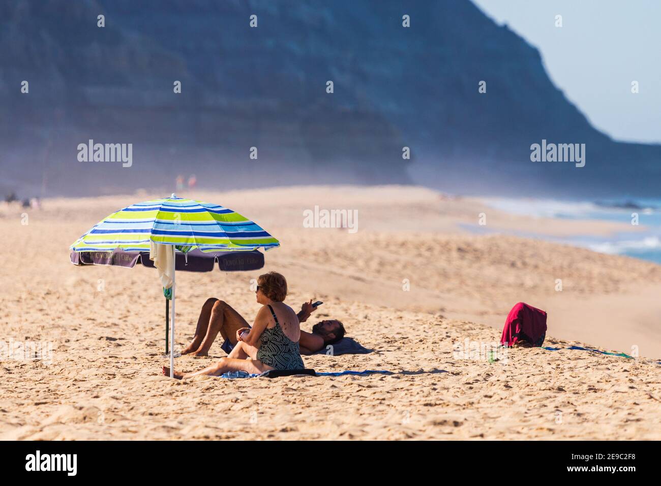 Portogallo, Praia Santa Rita Norte, 04 ottobre 2018: Persone che si rilassano sulla spiaggia di sabbia sotto gli ombrelloni. Foto Stock
